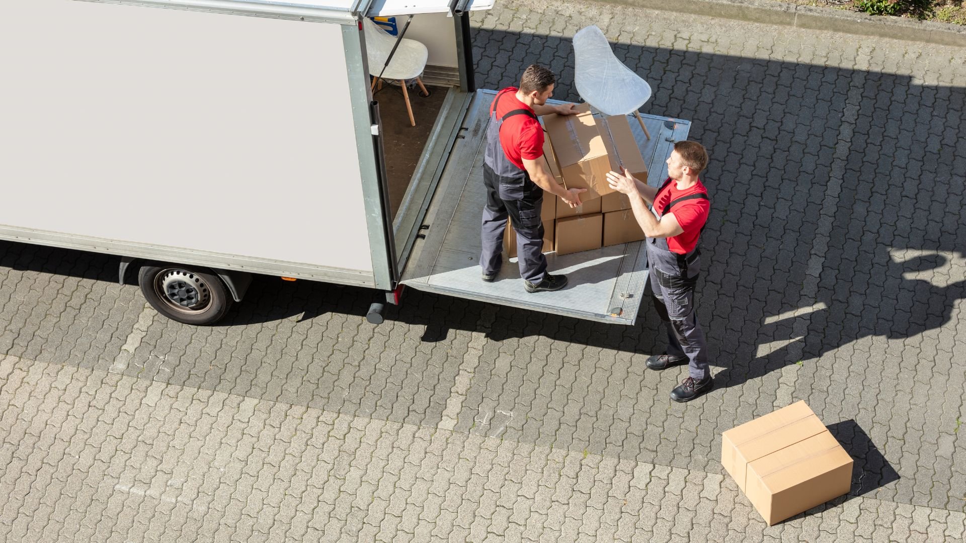 Two delivery workers unloading cardboard boxes from a white truck