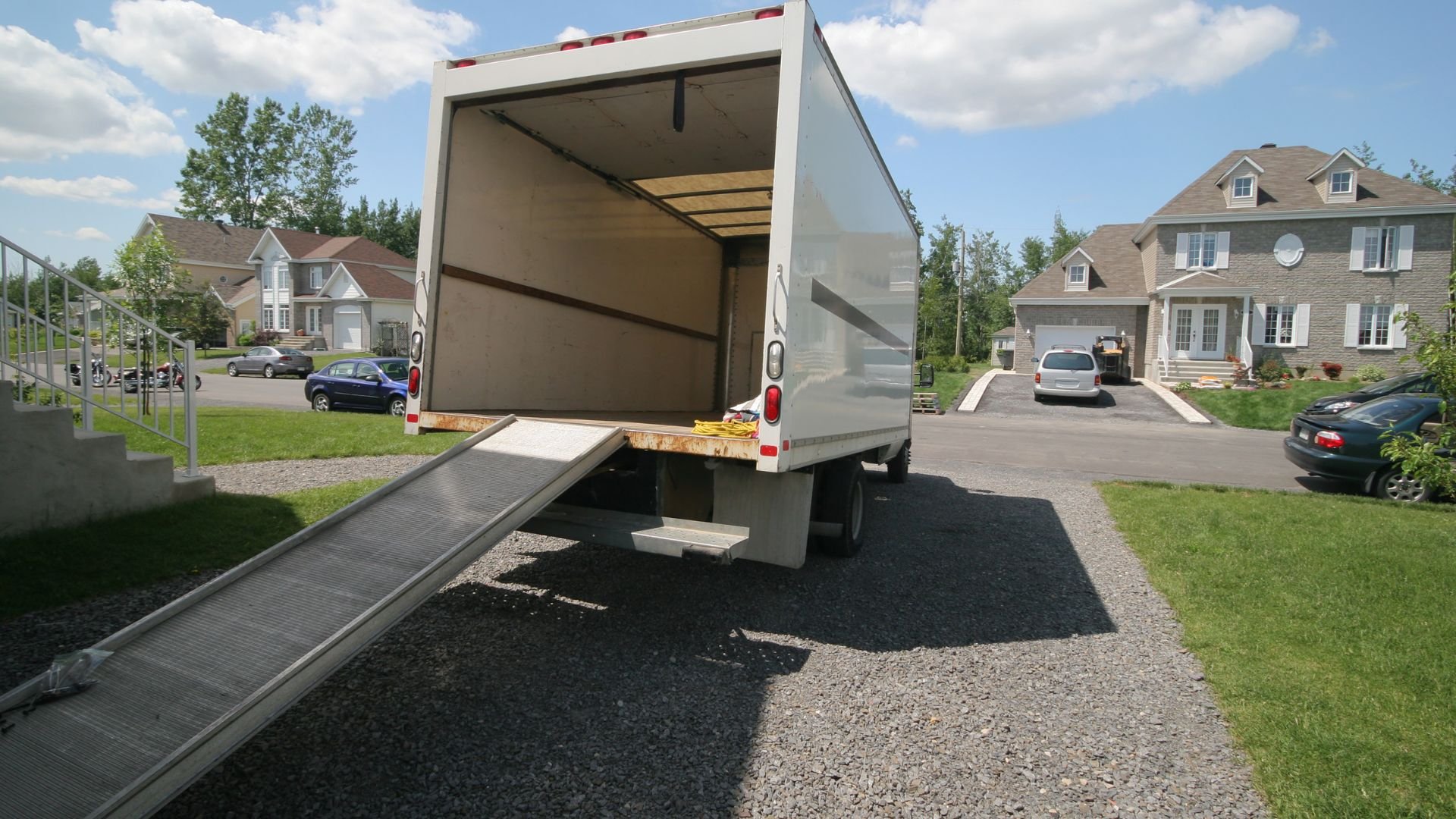 Large moving truck with ramp parked in residential suburban neighborhood
