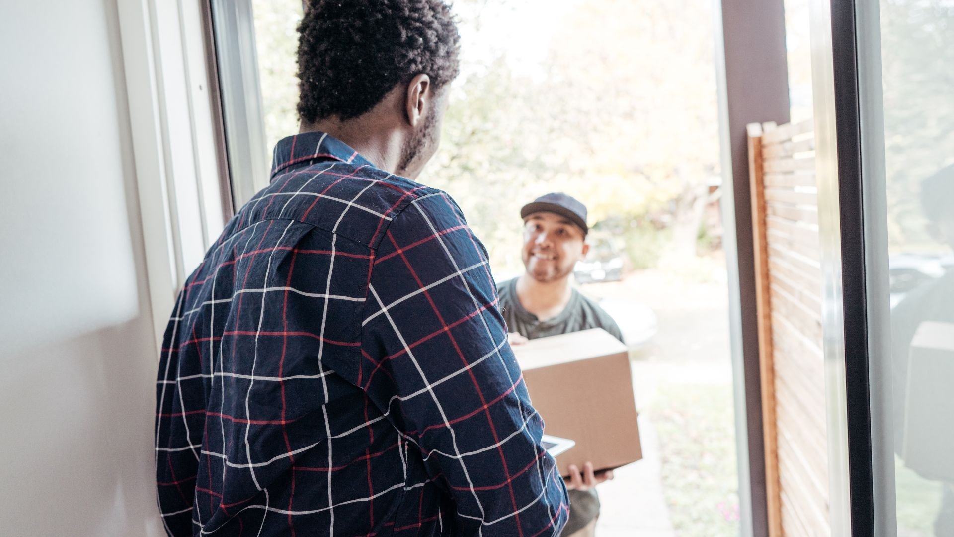 Delivery person handing package to recipient at home doorway