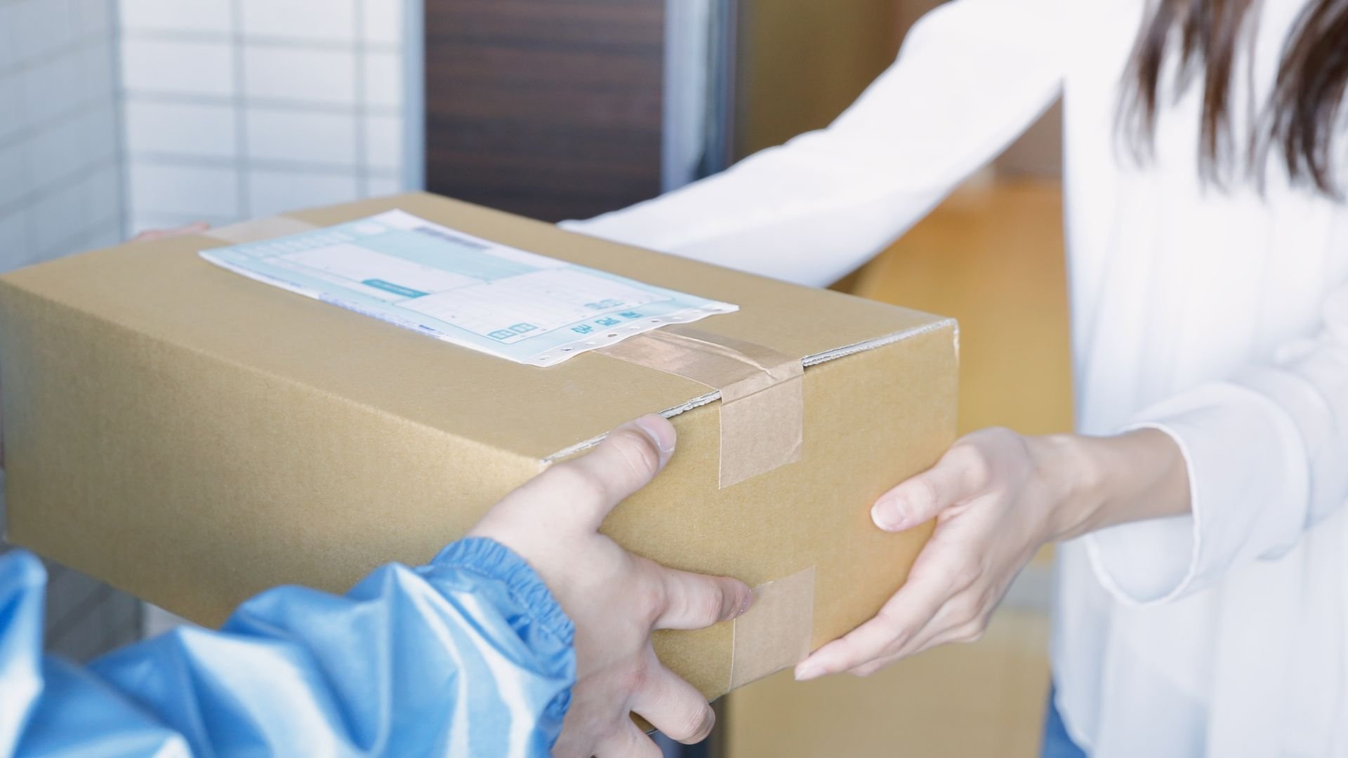 Hands exchanging a cardboard package with shipping label