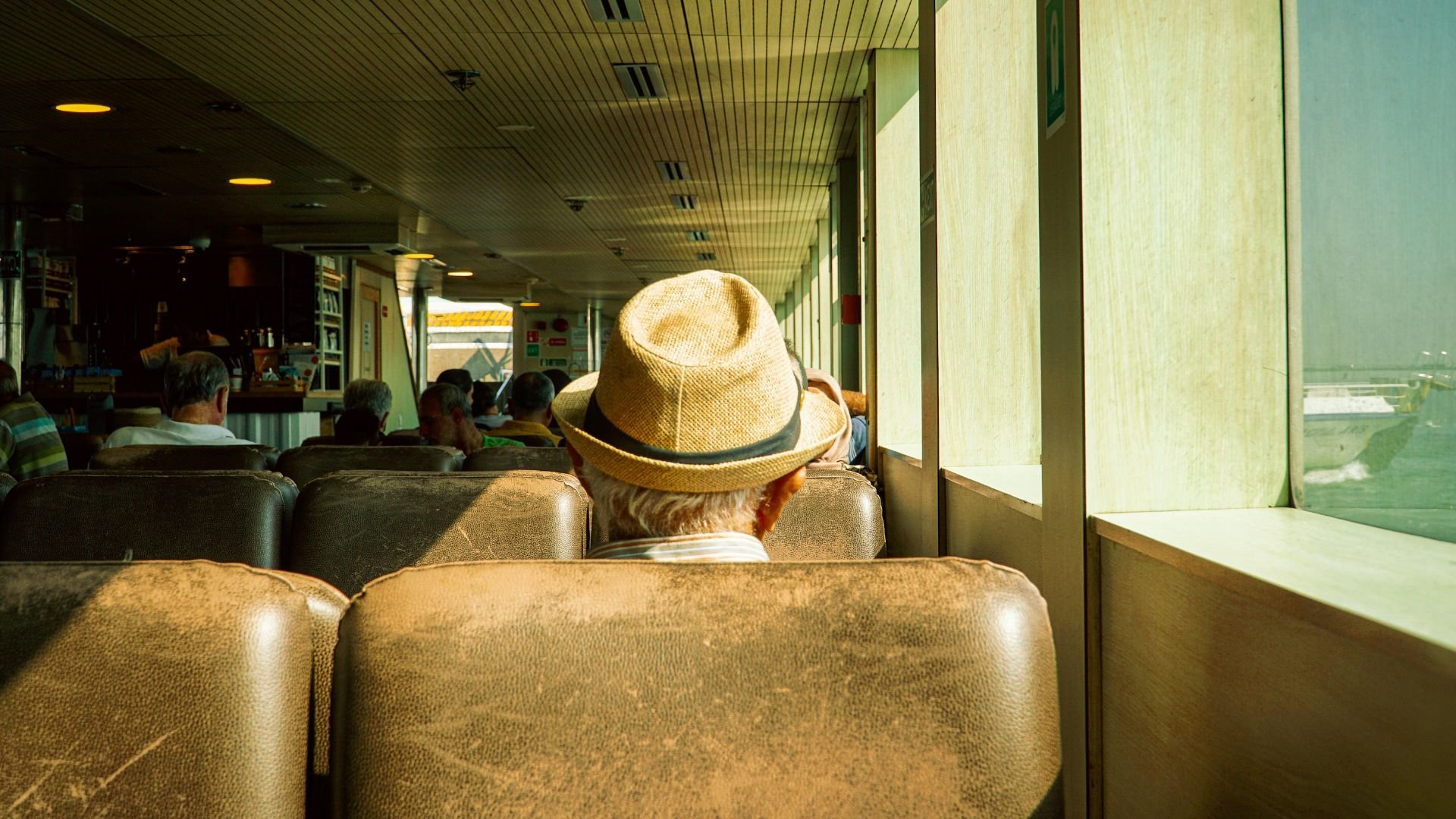 Person in straw hat sitting on bus, looking out window at sunny day