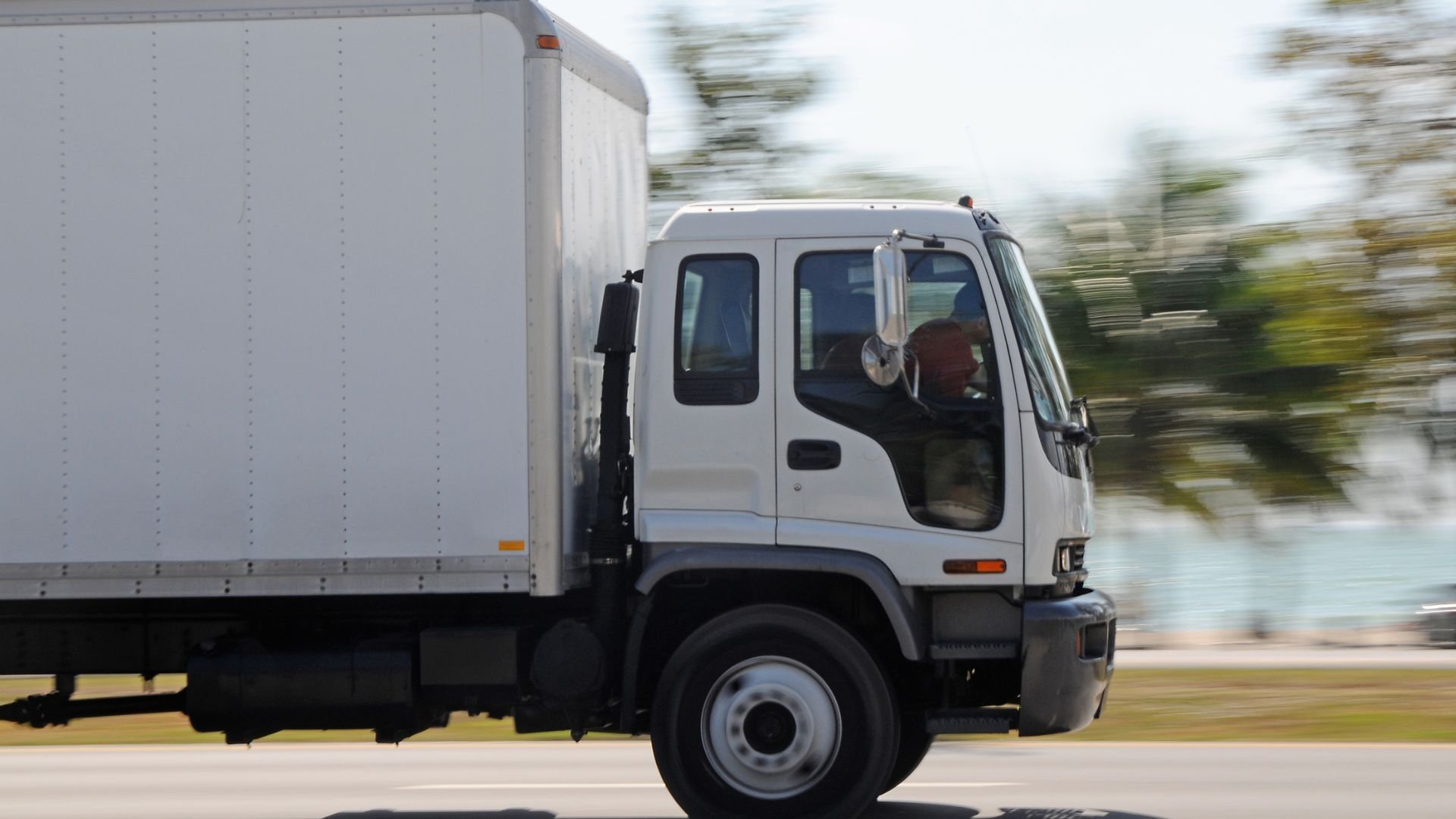 White delivery truck driving on road with blurred background